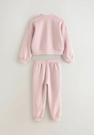 Růžový dvoudílný set, který obsahuje zkrácenou mikinu s žebrovanými manžetami a odpovídajícími tepláky. Na zadní straně mikiny je vyraženo "BAKER".