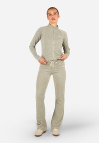 Gaiši pelēks ribots sporta uzvalks ar jaku ar rāvējslēdzēju un biksēm ar auklu jostasvieta. Izgatavots no mīksta auduma ar pieguļošu dizainu un smalkiem akcentiem.