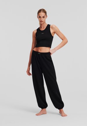 Black cropped tank top and loose-fitting black jogger pants. Soft cotton material, elastic waistband, and ribbed texture around the neckline.