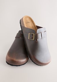 Braune Lederschuhe mit kontrastierendem grauem Obermaterial, ausgestattet mit einem Schnallenriemen, Kork-Fußbett und einer strukturierten schwarzen Gummisohle.