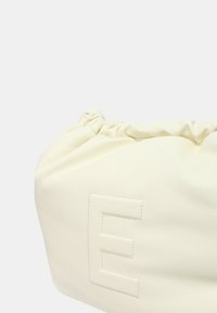 Borsa in pelle color crema con parte superiore arricciata e lettera "E" embossata sul lato. Texture liscia con design minimalista.