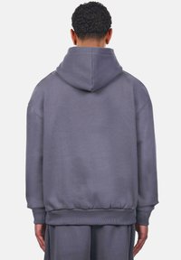 Grauer Hoodie mit großer Rückentasche, gerippten Bündchen und Saum, mit einer Kapuze mit Kordelzug und einem lockeren Schnitt. Weiches Material und minimalistischem Design.