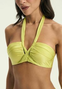 Jasnozielony bikini top typu bandeau, wykonany z gładkiego, elastycznego materiału, z przekręconym przodem i ramiączkami na szyję.