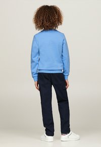 Blauwe sweater met ribgebreide manchetten en zoom, gecombineerd met marineblauwe cargo broeken met zijzakken, afgewerkt met witte sneakers.