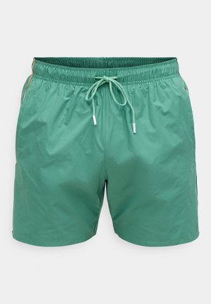 Pantaloni de înot verzi, cu talie elastică și șnur. Confecționați dintr-un material neted și ușor. Buzunare laterale și detalii minime de cusături.