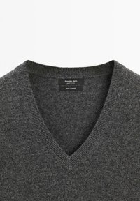 Pullover grigio in cashmere con scollo a V e dettagli a coste sul colletto e sull'orlo. Le etichette indicano il marchio, il paese di fabbricazione e la composizione del materiale.