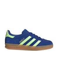 Baskets Adidas Gazelle bleues avec des bandes vert clair et languette au talon, semelle en gomme, et texte doré "GAZELLE" sur le côté.