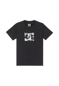 Camiseta de algodón negra con un logo blanco de DC en el centro, que incluye una estrella y un patrón abstracto. Manga corta, diseño de cuello redondo.