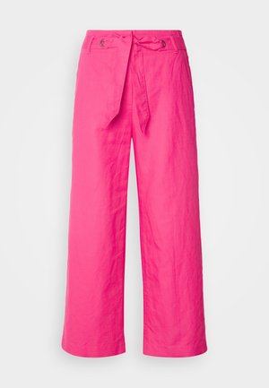 Różowe lniane spodnie w szerokim kroju z wiązaniem w talii, z teksturowaną powierzchnią i metalowymi akcentami w okolicy talii.
