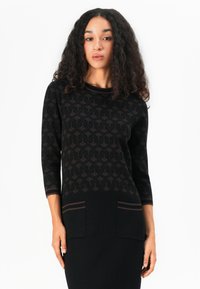Pull en tricot noir avec un motif à losanges, col rond, manches trois-quarts et deux poches plaquées à l'avant.