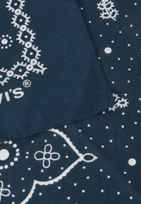 Navy blue fabric with white floral and geometric patterns, featuring small dots and detailed stitching along the edge.