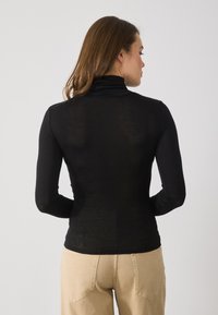 Schwarzes Langarm-Turtleneck-Oberteil aus leichtem, dehnbarem Material. Verfügt über ein enganliegendes Design mit einer glatten Textur.