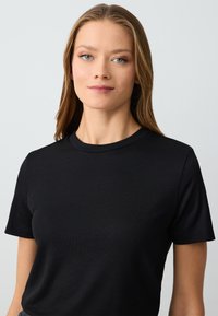 Zwarte geribbelde t-shirt met korte mouwen, voorzien van een ronde halslijn en een gestructureerde stof. Eenvoudig, aangesloten ontwerp.
