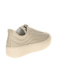 Beżowe skórzane sneakersy z grubą, białą podeszwą platformową. Charakteryzują się wyszywanymi falistymi wzorami po bokach oraz delikatną pętelką z tyłu.