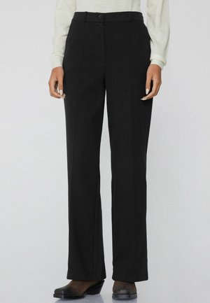 Zwarte wijde broek van gladde stof met een hoge taille, knoopsluiting en voornaaddetails. Gecombineerd met zwarte hakken.