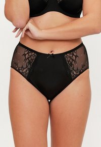 Culotte noire taille haute en tissu lisse, avec des panneaux en dentelle, des motifs floraux et un petit nœud central à la taille.