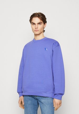 Purple sweatshirt made of cotton. Features a round neck and long sleeves. Accented with a small blue bird logo on the left chest area.