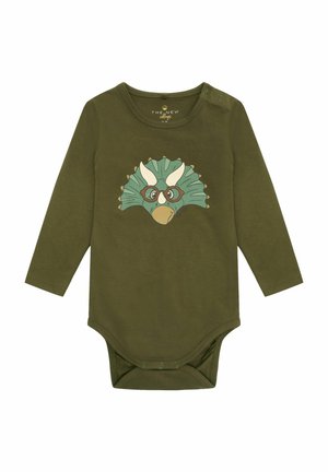 Oliivinvihreä pitkähihainen bodysuit, joka on valmistettu pehmeästä puuvillasta. Edessä on painettu dinosauruksen kasvot silmälasien kanssa ja alhaalla neppari.