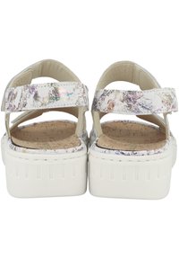 Sandales à plateforme blanches avec des lanières colorées à motifs, semelle en liège et semelle blanche texturée. Elles possèdent deux lanières croisées pour le support.
