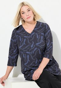 Tunic nera con scollo a V e maniche a tre quarti, caratterizzata da un motivo di piume blu. Il tessuto morbido si drappeggia dolcemente sul corpo.