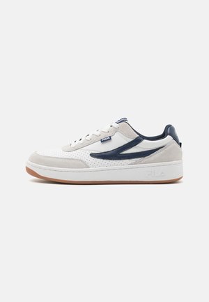 Sneaker bianca e grigia con tomaia perforata, dettagli in suede liscio, logo blu navy e suola in gomma; design a profilo basso.
