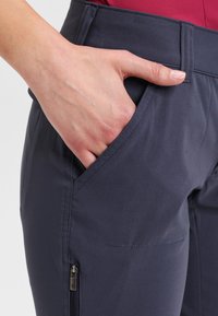 Pantaloni outdoor navy con una texture liscia, dotati di una tasca frontale e una tasca laterale con zip per una conservazione sicura.