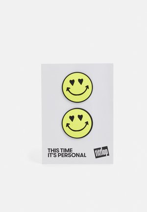 Adesivos de caras sorridentes amarelas com corações nos olhos, exibidos num cartão branco com texto preto que diz "Desta vez é pessoal."