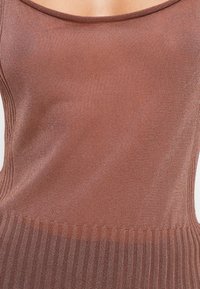 Brun ribbestrikket tank topp med en glatt, tett passform og scoop-halsutskjæring, samt teksturert nedre kant. Ingen ytterligere mønstre eller detaljer.