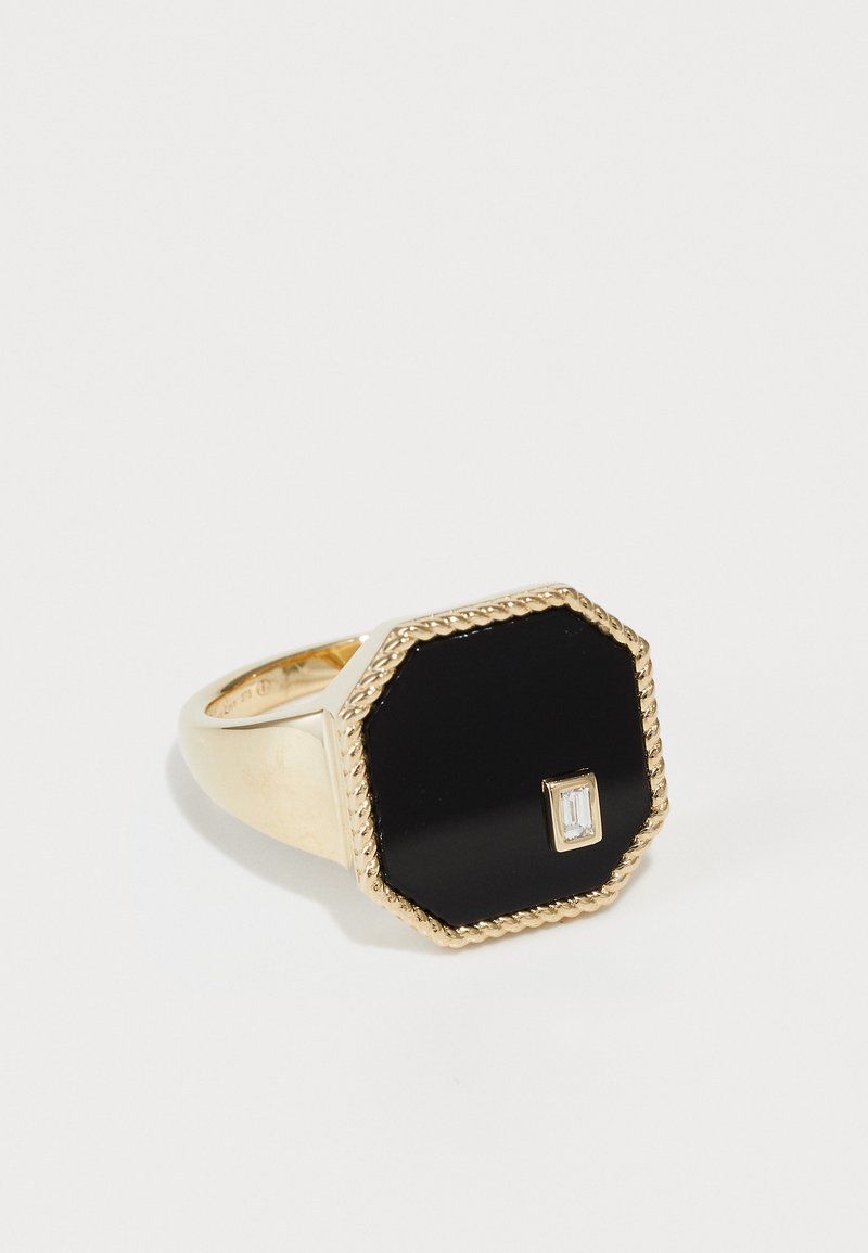 Gold-tone ring with an octagonal black stone, featuring a small rectangular clear accent. Textured twisted border detail around the stone.
