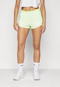 Shorts de sport légers, de couleur vert n�éon, avec une taille élastique et des poches latérales. Associés à des baskets blanches et des chaussettes présentant des logos noirs.