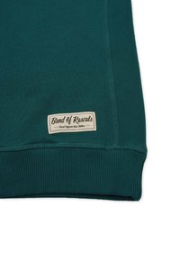 Grön sweatshirt med ribbade ärmslut, en slät textur på kroppen och en tygetikett som visar "Band of Rascals" på fållen.