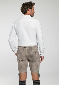 Witte langsgemiddelde shirt met een kraag, gedragen met grijze suède shorts met zijden veters en een achterzak met knoopsluiting.