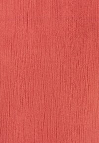 Tecido texturizado em cor coral, apresentando um padrão de superfície pregueada. Textura suave com uma sensação lisa e sutis variações de tonalidade.