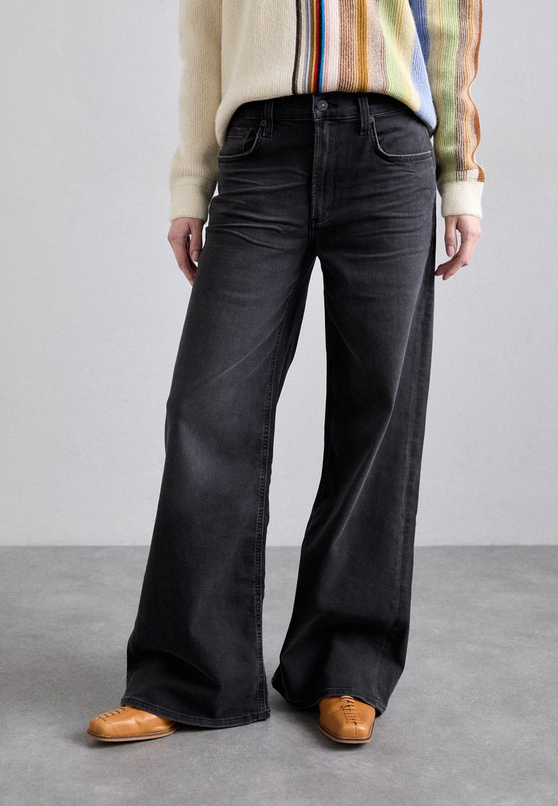 Wide-leg black denim jeans with faded texture, five pockets, and belt loops. Pairing with brown leather shoes.