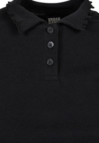 Svart ribbet polo-skjorte med slitt krage og tre svarte knapper, som har en myk tekstur og et uformelt design.
