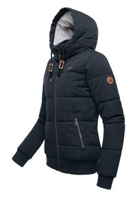 Jūros mėliso pūkuotas švarkas su kapišonu, užsitraukiamas užtrauktuku, viduje aptrauktas flisu, su rudos odos akcentais ant rankogalių ir krūtinės.