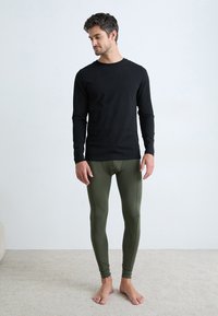 Black long-sleeve shirt and fitted olive green leggings, both made from smooth fabric, featuring a simple design and snug fit.