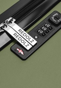 Groene harde koffer met een zwart cijferslot en twee zilveren ritsen met het label "REDOLZ" vergrendeld in het slot.