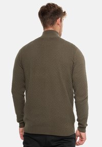 Olive green sweater with a textured herringbone pattern, ribbed collar and cuffs, and a fitted silhouette.