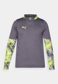 Grey athletic shirt with a quarter-zip collar. Long sleeves feature a vibrant green and grey abstract pattern. Logo on chest.