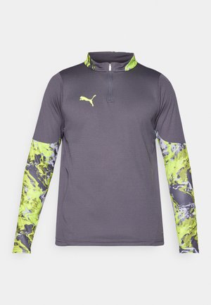 Grå träningsskjorta med en kvart-zipp krage. Långa ärmar har ett livligt grönt och grått abstrakt mönster. Logotyp på bröstet.