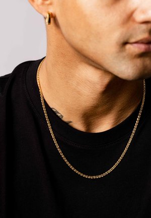 Goldkette mit miteinander verbundenen Gliedern, getragen über einem schwarzen T-Shirt; hat eine glatte Textur und ein einfaches Design.