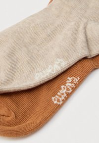 Μπεζ και καφέ βαμβακερές κάλτσες, με ραβδωτή υφή και αντιθετικά χρώματα, με κεντημένα λογότυπα της μάρκας σε λευκό σε κάθε κάλτσα.