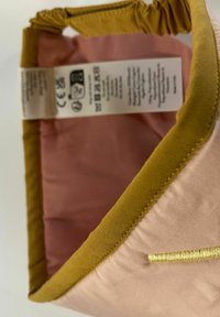 Ružový textilný kontajner so žltým lemovaním. Má skladaný vrchný okraj a vnútornú etiketu s pokynmi na starostlivosť.