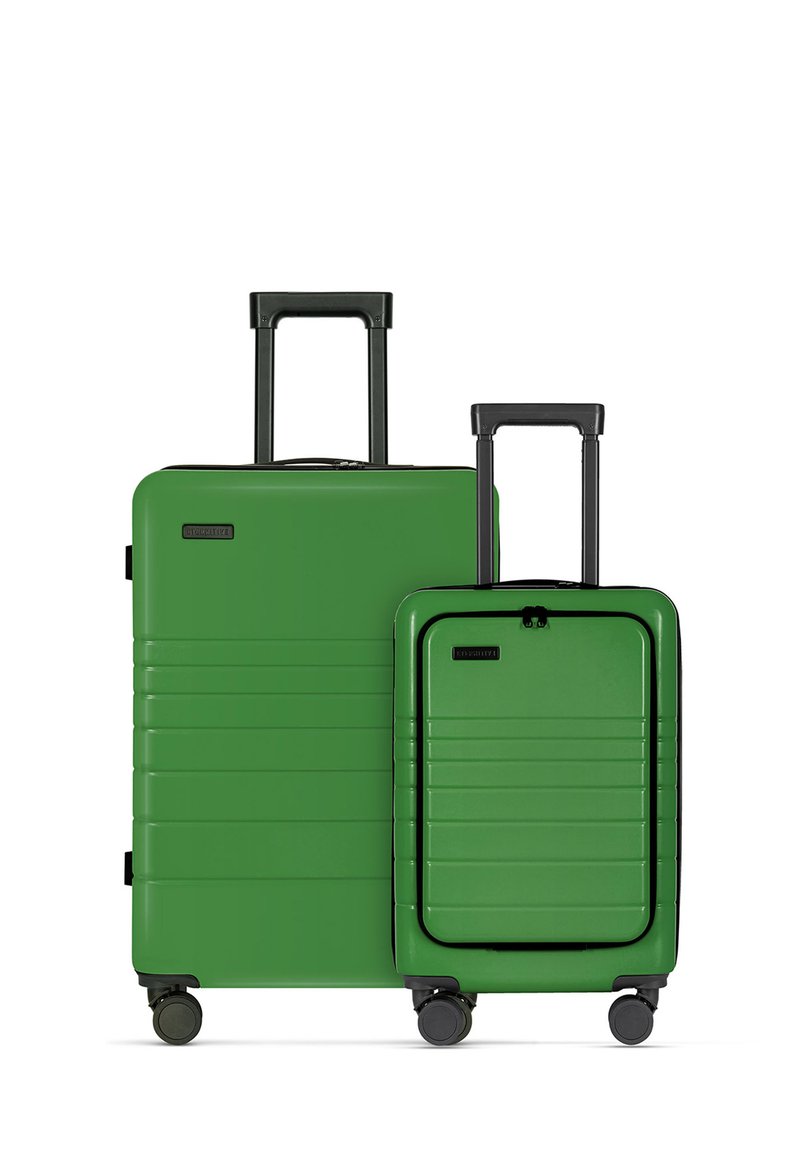 Twee groene harde koffers van verschillende maten met verticale groeven, zwarte accenten en uitschuifbare handvatten; op wielen voor mobiliteit.
