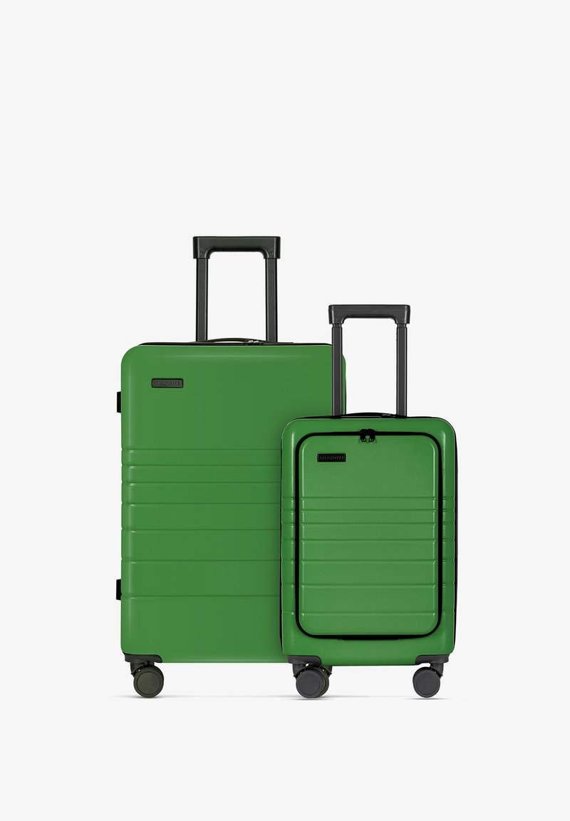 Twee groene harde koffers van verschillende maten met verticale groeven, zwarte accenten en uitschuifbare handvatten; op wielen voor mobiliteit.