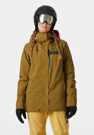 Olivengroene skijack met een capuchon en zwarte accenten, voorzien van een ritszak en manchetten. Draag met gele skibroek en zwarte handschoenen.