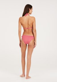 Bikini rosa a coste con design a collo all'americana, dotato di spalline regolabili e chiusura sul retro. I culotte hanno lacci laterali per una vestibilità sicura.