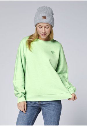 Minzgrüner Pullover mit gerippten Bündchen und Rundhalsausschnitt, versehen mit einem kleinen Logo. Kombiniert mit einer hellgrauen, gerippten Mütze.