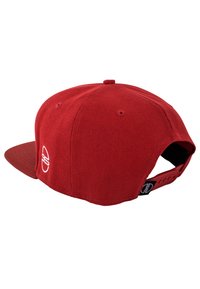 Red corduroy cap with a flat brim, featuring a white logo on the back. Adjustable strap in black at the back. Texture is ribbed.